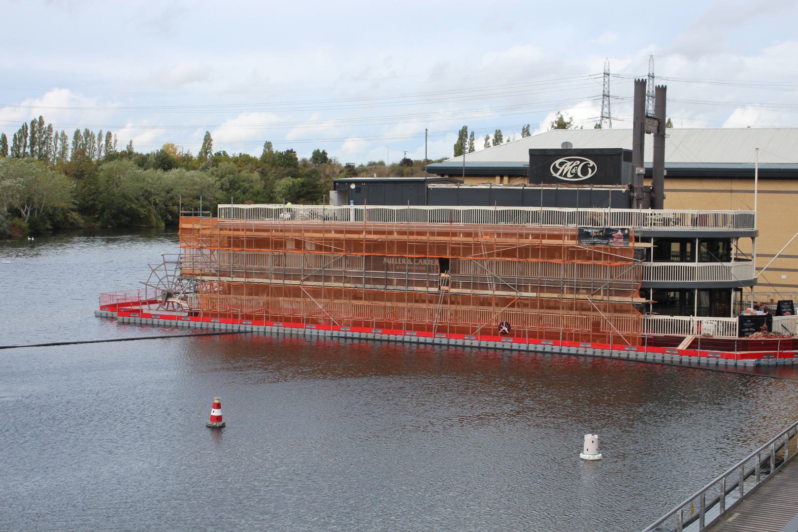 Modular floating pontoon platform supporting scaffolding and refurbishment works along a large waterfront commercial building